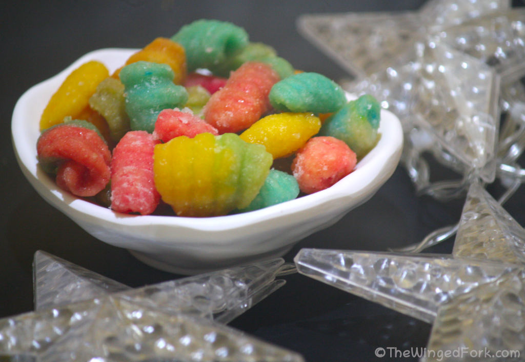 Colorful sweets called kulkuls in a white bowl next to plastic stars.