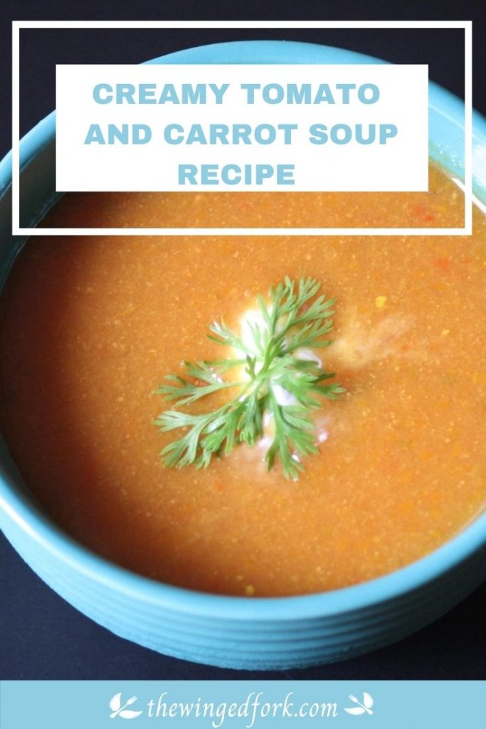 Tomato and carrot soup in a blue bowl with coriander and cream on top