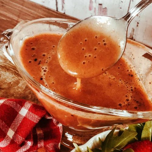 Date and strawberry balsamic dressing in a glass bowl with a spoon.