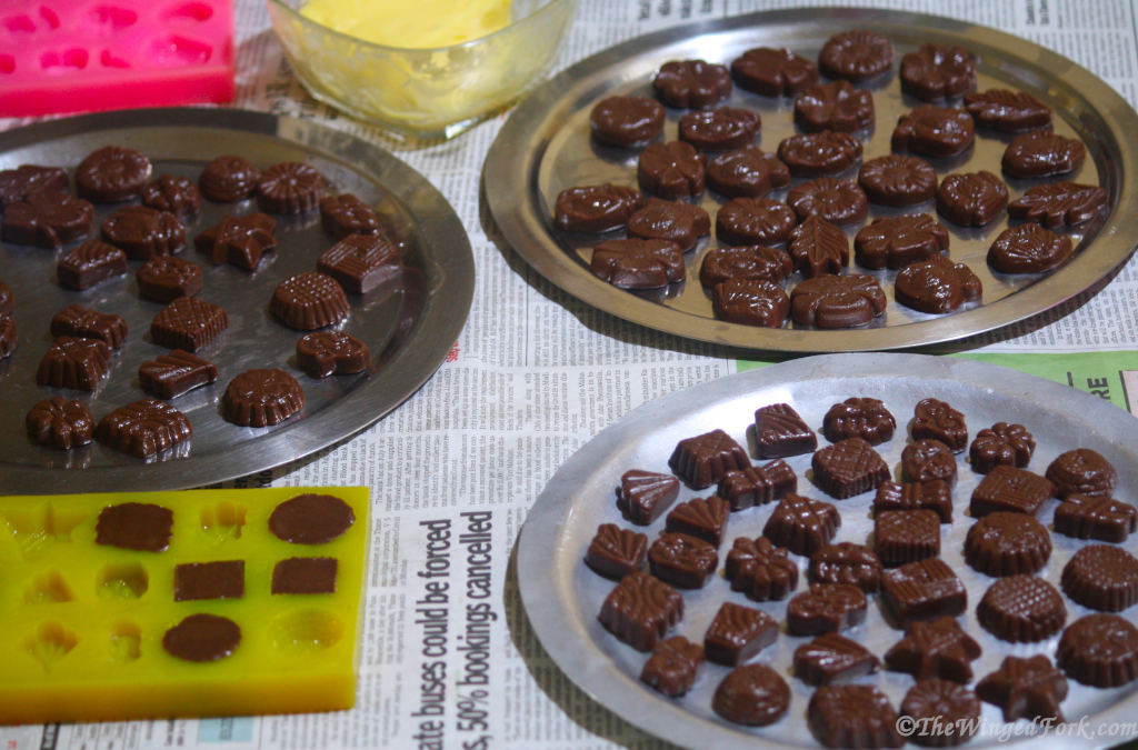 Walnut fudge on 3 steel thalis with a bowl of butter and silicon moulds nearby.