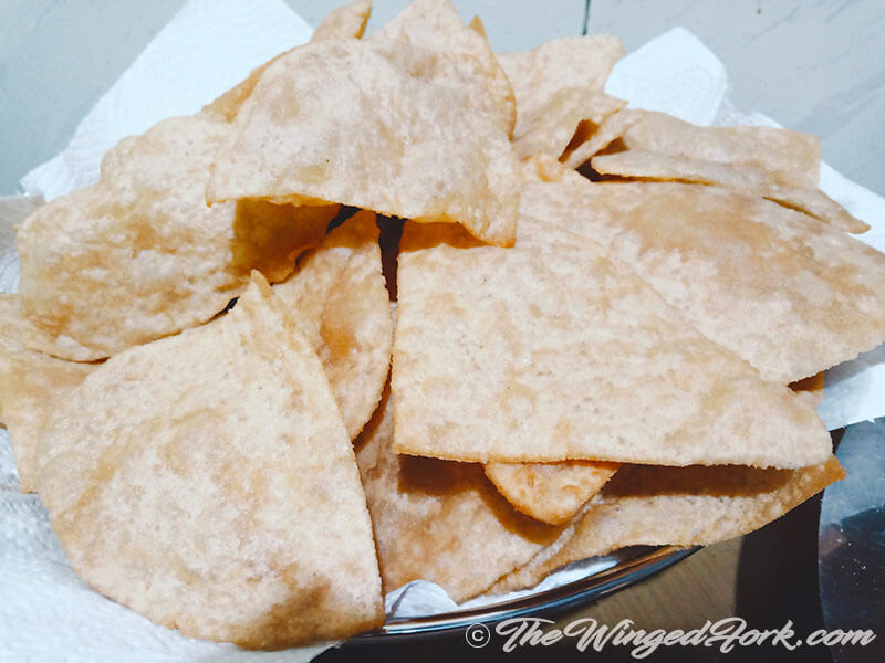 Crispy triangular puris on a bed of tissue paper.
