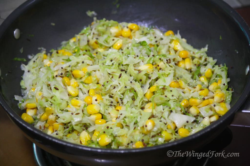 Cabbage and corn stir fry in a black pot.