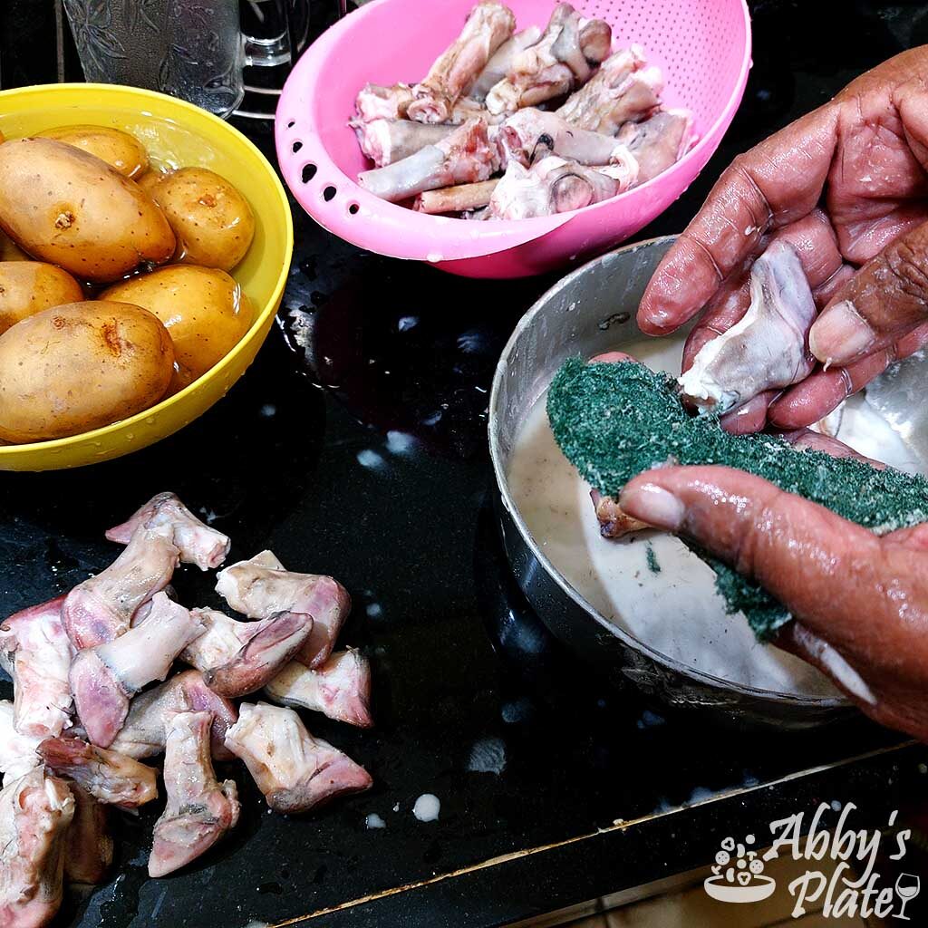 Washing goat trotters with rice flour and a scrubber.