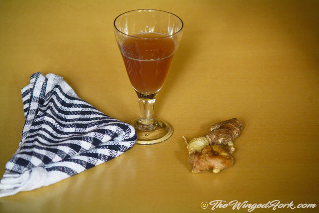 Pic of a glass of Ginger Wine next to a piece of ginger and a kitchen towel - Pic by Abby from AbbysPlate