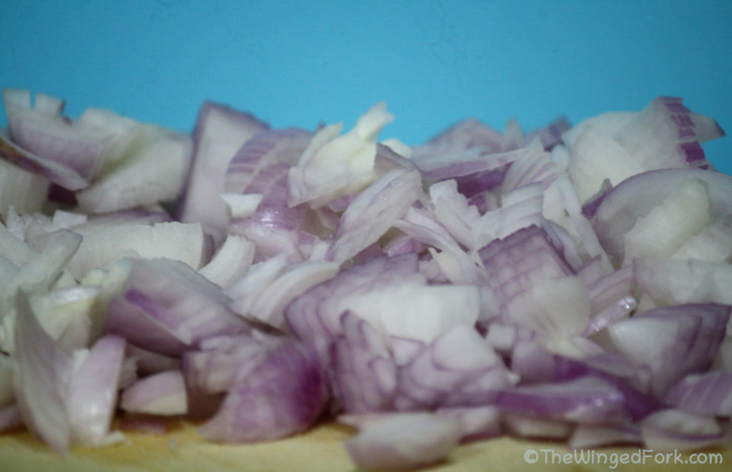 Chopped Onions on a brown board with a blue background