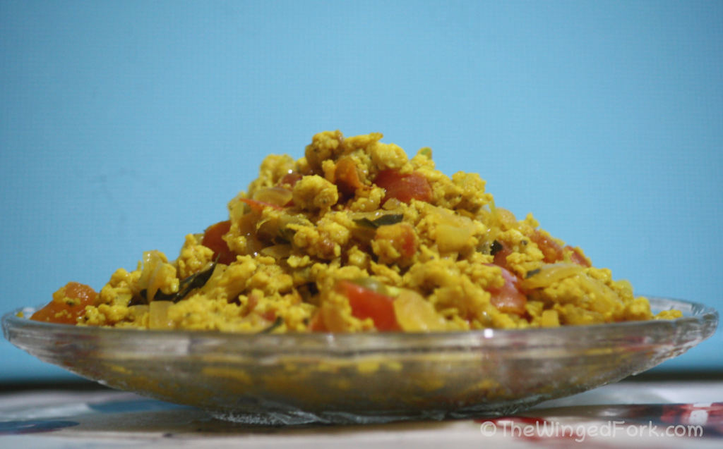 Egg bhurji ready to serve in a glass plate against a blue background