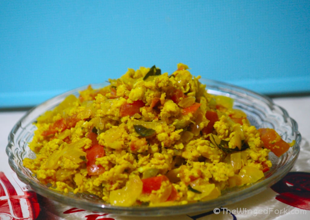 Tasty egg bhurji in a glass plate in front of a blue board