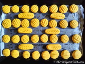 Yellow coloured custard powder cookies cooling in a baking tray.