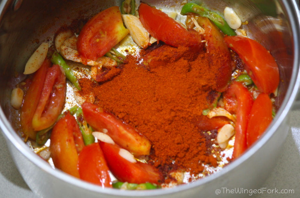Chilli powder and garam masala added to the ingredients in the stainless steel pot.