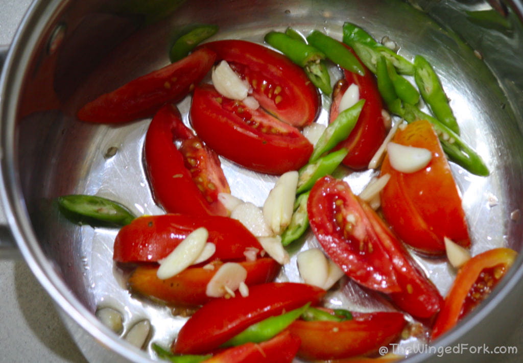 Chopped tomatoes, chillies and garlic in a steel vessel.