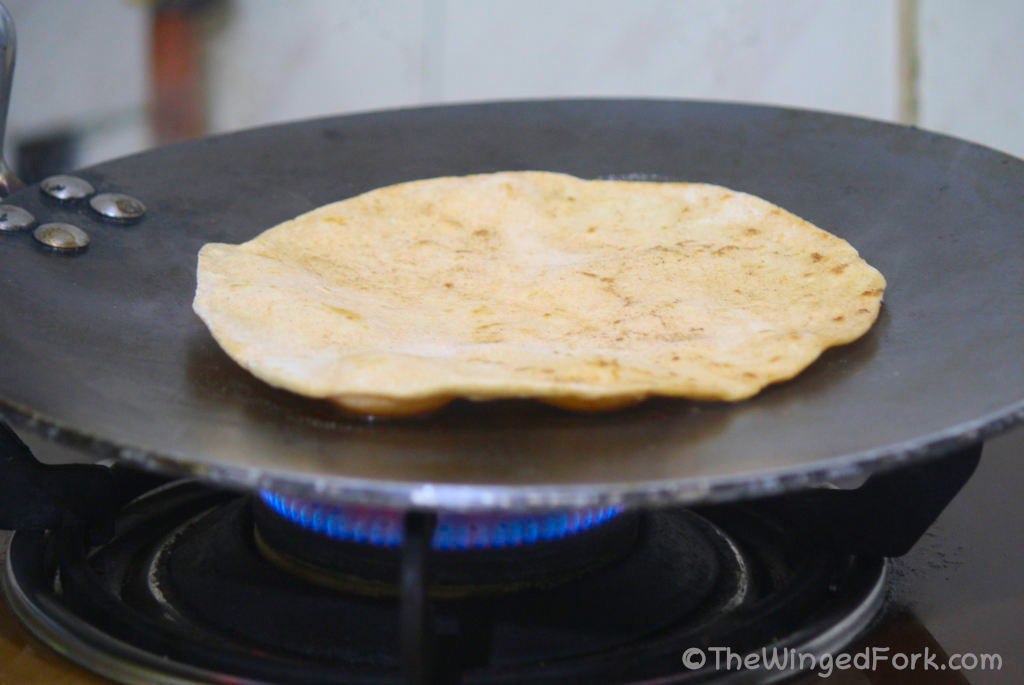 Chapati cooking on the other side on a hot tawa or frying pan.