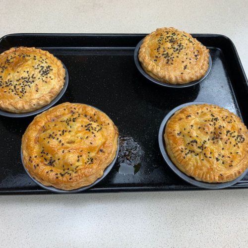 Baked pies on a black tray.