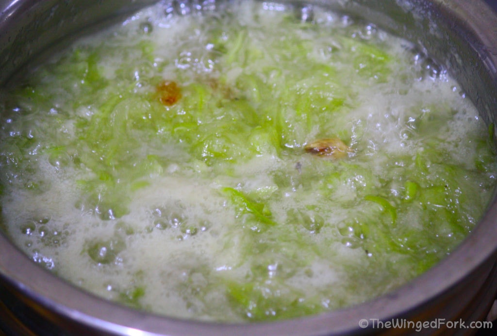Grated bottle gourd, sugar and cardamom boiling in a vessel.