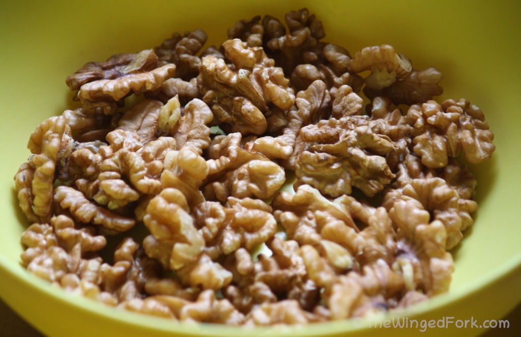Whole walnuts in a yellow bowl.