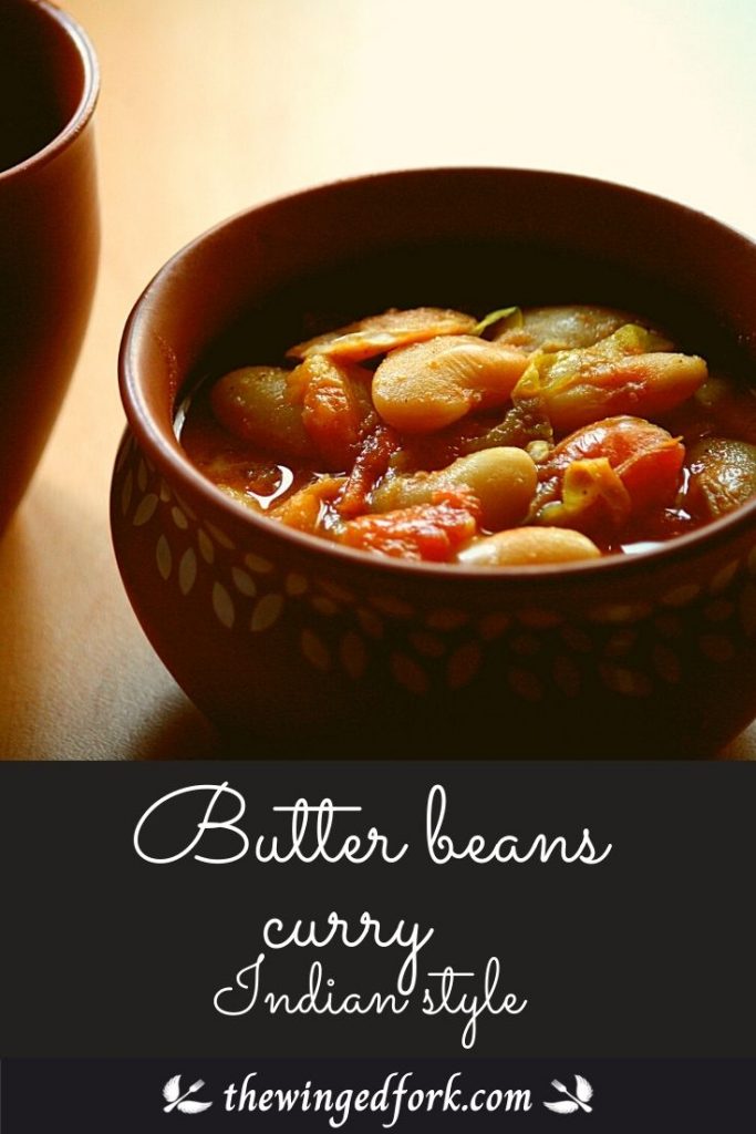 Pinterest Image of a earthen vessel serving butter beans curry and a part of a water glass next to it.