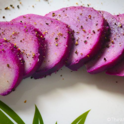 Purple yam slices on a plate sprinkled with salt and pepper.