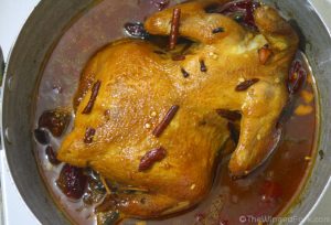 Top view of whole Roast Chicken cooking in a vessel with spices and gravy.