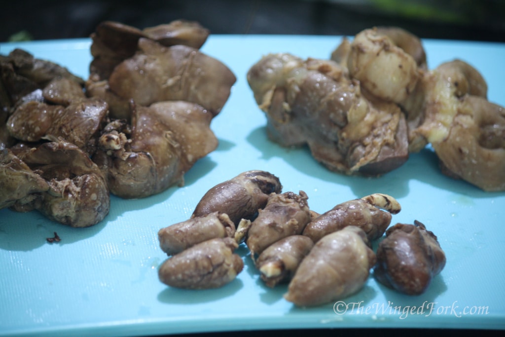 Chicken giblets - hearts, livers and stomachs on a blue chopping board.
