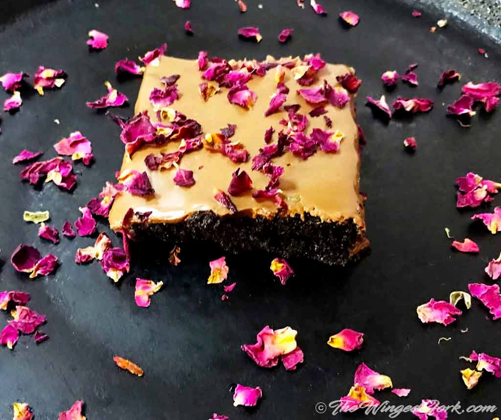 Rum and raisins brownie with chocolate and rose petals.