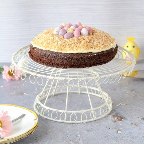 A Easter nest cake on a white cake stand.