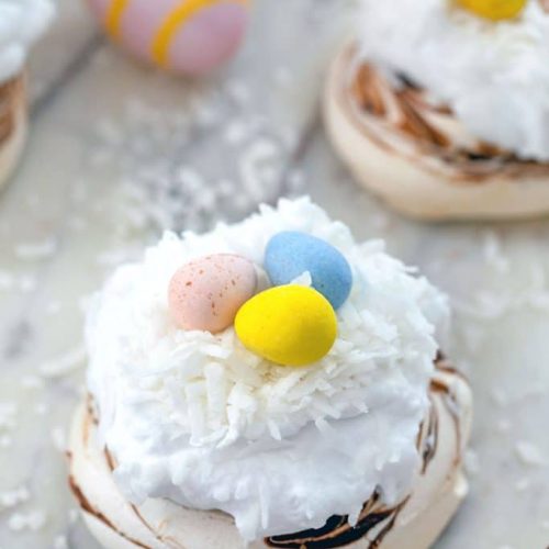 White colored Easter pavlova with cadbury eggs on top.