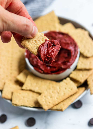 Red Velvet cheesecake dip and crackers on a white surface.