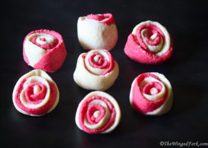 Pink and White rose cookies on a black surface.
