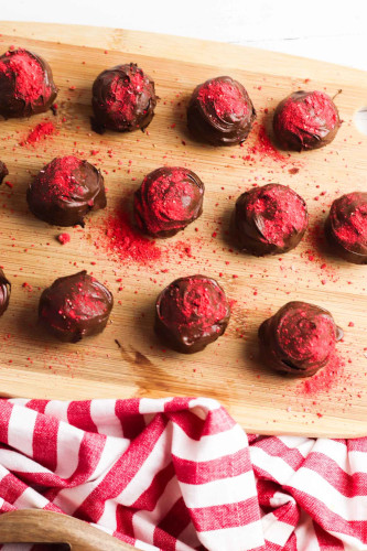 11 Strawberry truffle places on a wooden board.