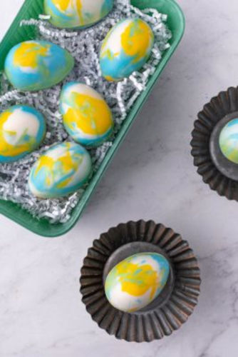 Blue, white and yellow coloured Easter Eggs made of chocolate in a tray.