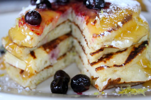 Lemon rocitta pancakes topped with berries and syrup.