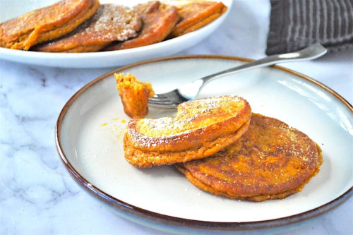 Spiced pumpkin pancakes on a plate with a fork.
