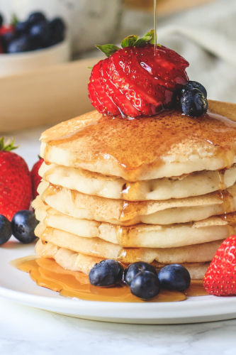 Eggless pancakes topped with berries and maple syrup.