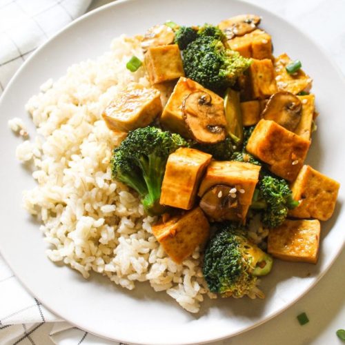 Mushroom and tofu served with white rice and broccoli in a plate.