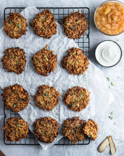 Air Fryer Latkes on a baking tray served with apple sauce.