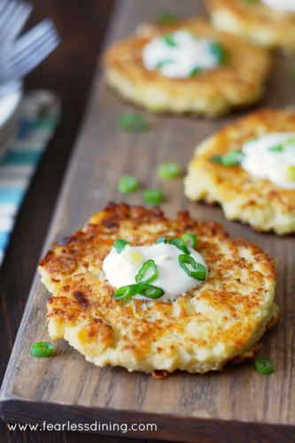 Cauliflower cheddar pancakes on a tray sprinkled with green onion.