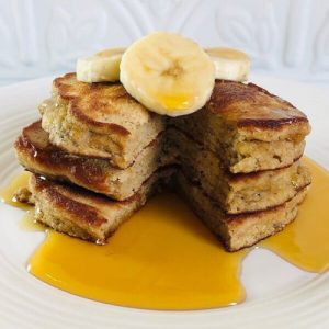 Paleo Banana Pancakes with a slice cut out topped with banana slices.