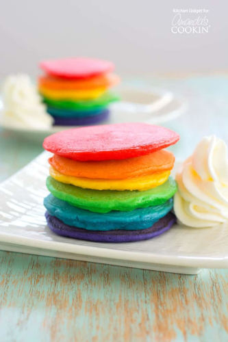 Rainbow pancakes in a plate with cream.