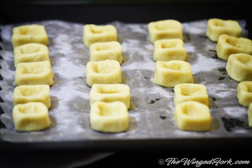 Square dough cups lined on a baking tray.