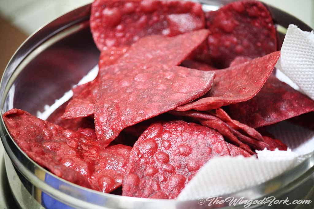 Triangular Pink puris kept on tissue paper to drain oil.