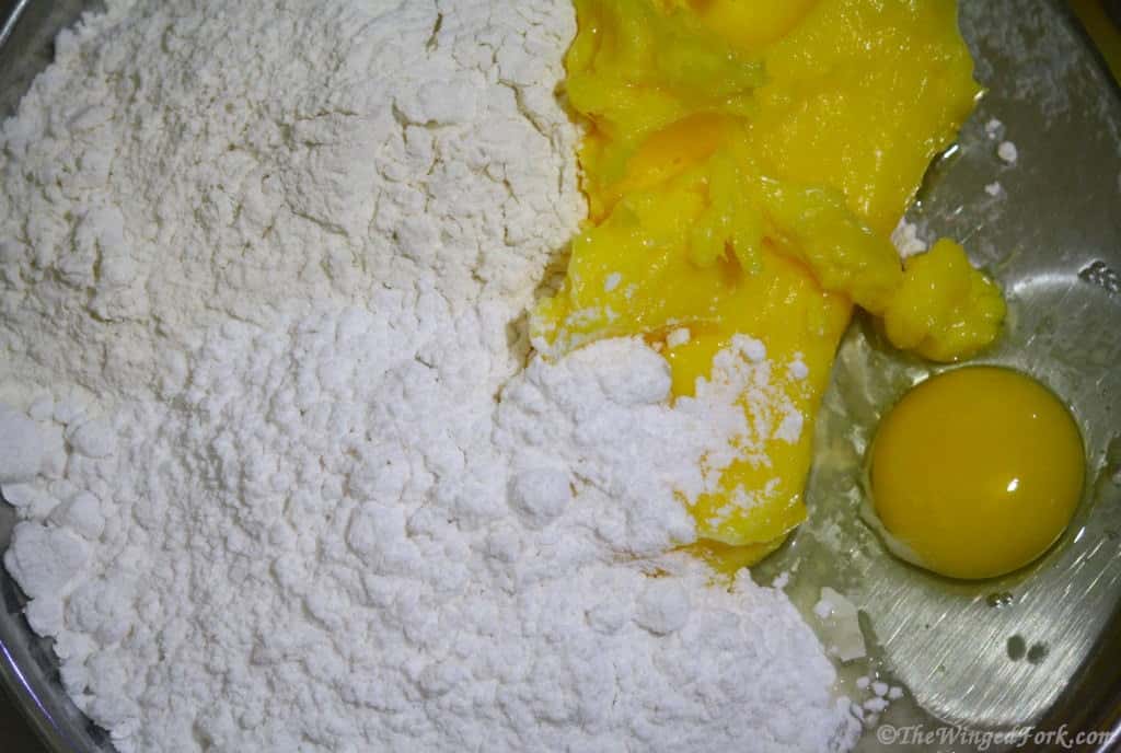 Flour, sugar, baking powder, butter and egg in a thali.