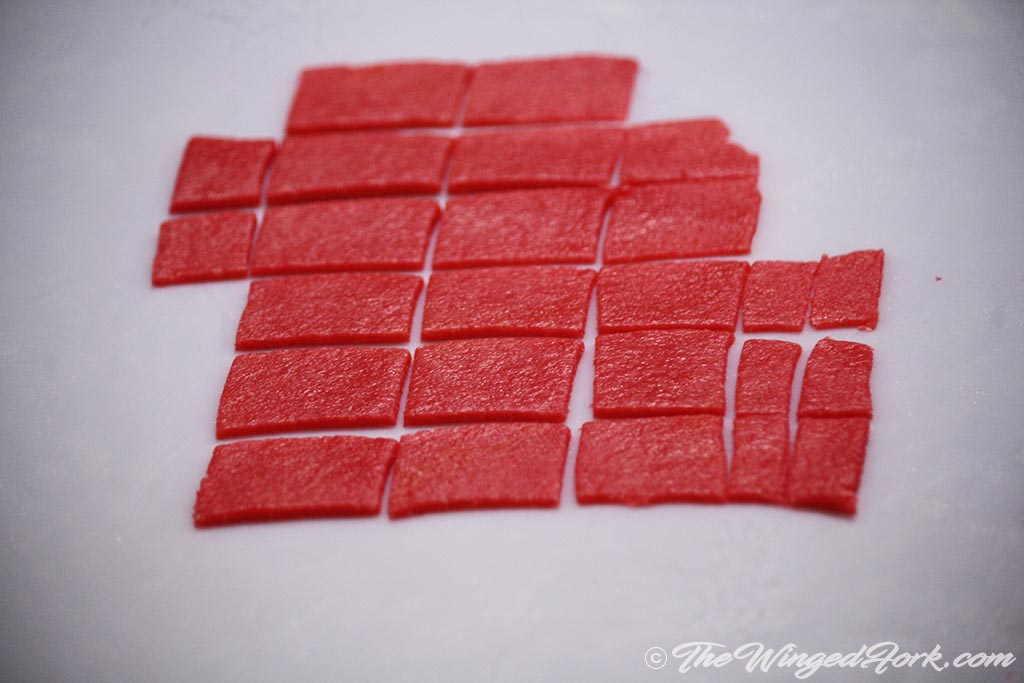 Rectangular pink pieces cut and kept on the white paper.