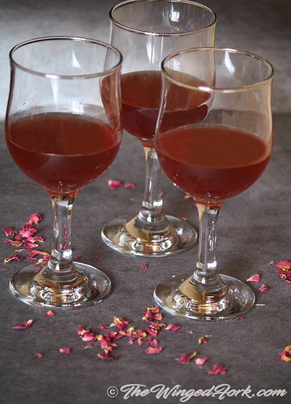 Rose wine served in wine glass with rose petals scattered.
