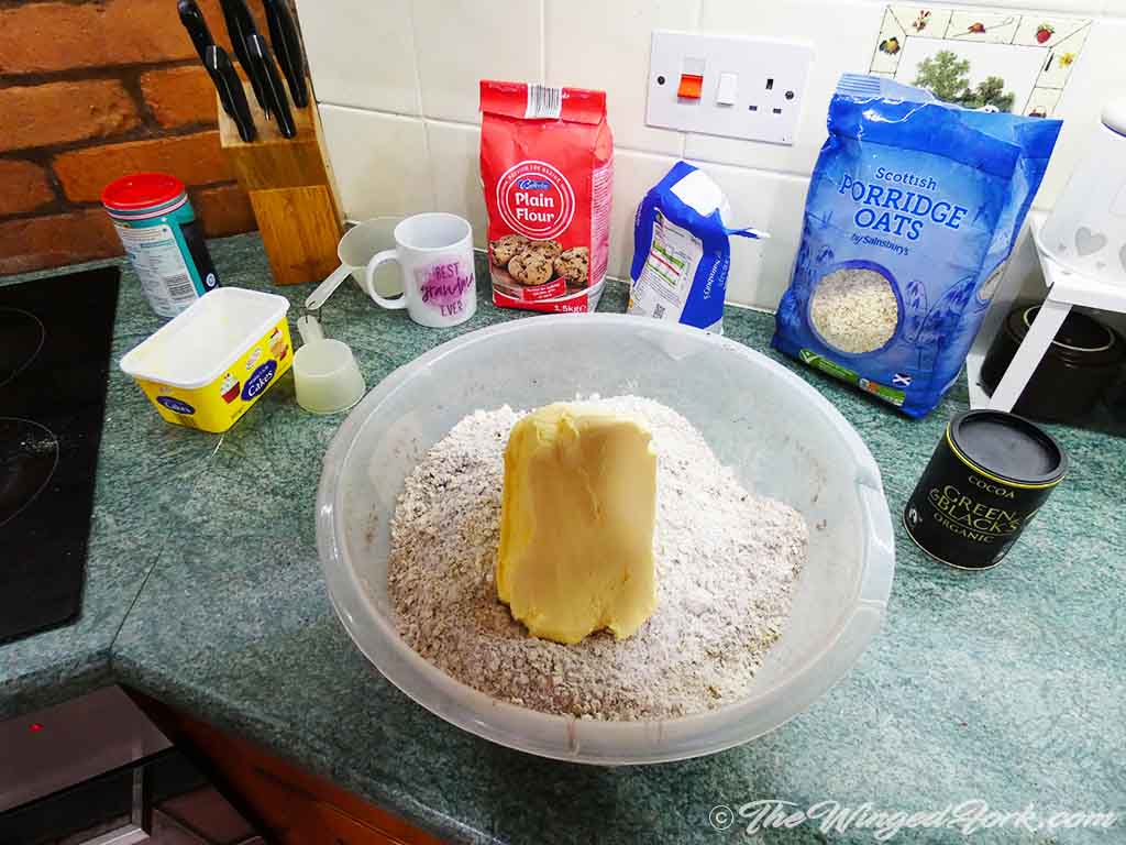 A big chunk of margarine on mixed flour in a bowl.
