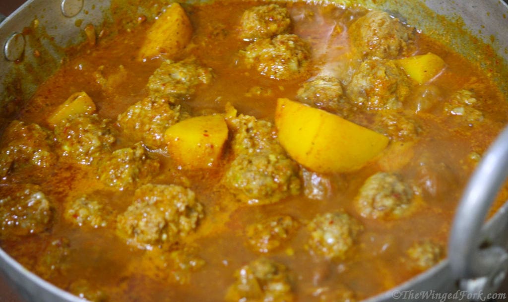 Meatballs and potatoes cooking in a kadai.