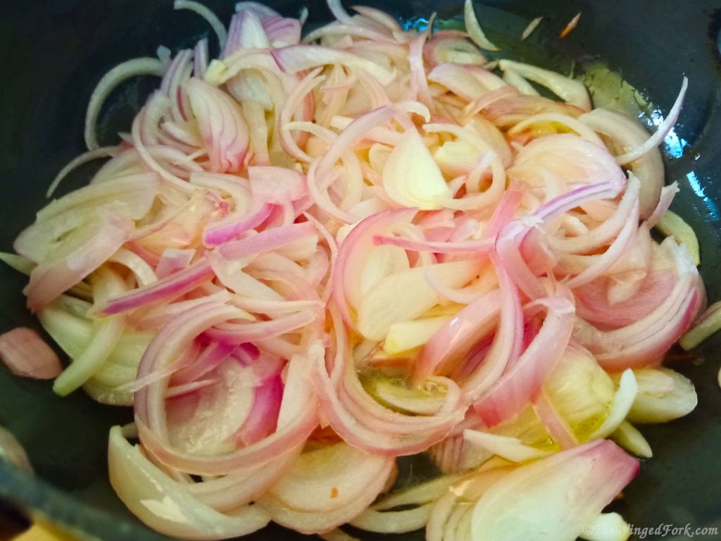 Sliced onions in a vessel with oil.