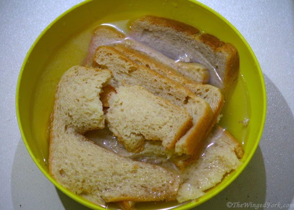 Brown bread soaking in water in a yellow bowl.
