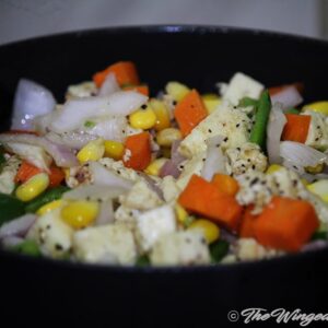 Stir fry veggies and indian cottage cheese in a wok.
