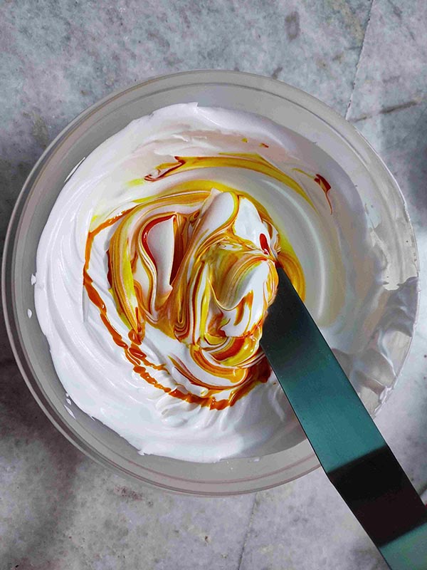 Add yellow colour to the white icing and start mixing.
