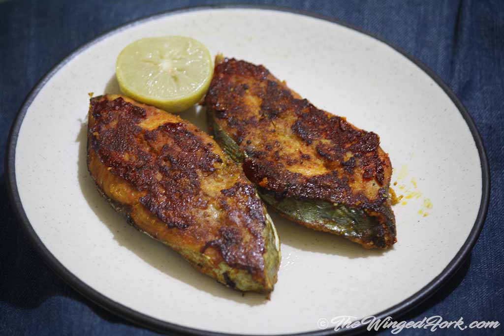 Serve fried king fish on a plate with lime.
