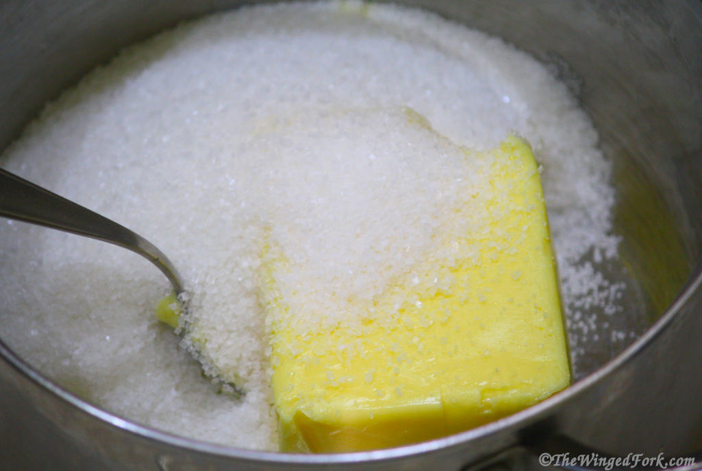 Sugar and butter in a vessel with a spoon.